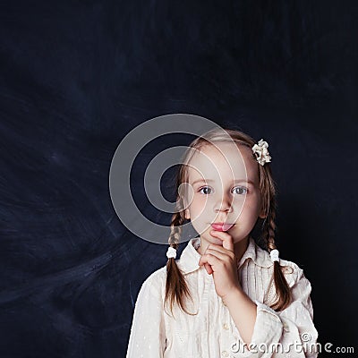 Ð¡urious child thinking. Little girl on chalk board background Stock Photo